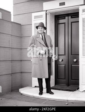 1950S HOMME D'AFFAIRES PORTANT UN MANTEAU DE DESSUS CACHEMIRE CHAPEAU TENANT DES GANTS DEBOUT DEVANT LA PORTE AVANT DOUBLE - S4429 CRR001 HARS PERSONNES PLEINE LONGUEUR RÉSIDENTIEL HOMMES BÂTIMENTS CONFIANCE B&W CONTACT VISUEL SUCCÈS STYLES PUISSANT FIERTÉ MAISONS HAUT DE GAMME AISÉS RÉSIDENCE ÉLÉGANTE PORTE D'ENTRÉE DEVANT LA PROSPÈRE MODE CACHEMIRE MOYEN-ADULTE MOYEN-ADULTE HOMME-À-FAIRE NOIR ET BLANC DE L'ETHNIE CAUCASIENNE VOLETS ANCIENS Banque D'Images