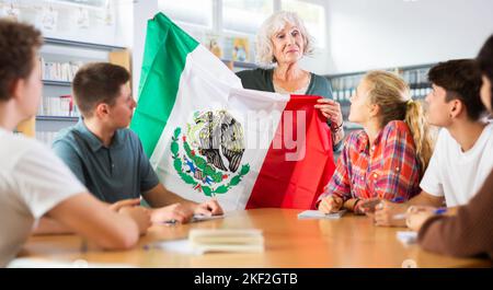 L'enseignante mature montre aux jeunes enfants le drapeau national du Mexique Banque D'Images