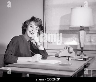 1960S FEMME SOURIANTE ASSISE À LA MAISON BUREAU AVEC STYLO TÉLÉPHONE LAMPE DE TABLE ÉCRIRE AVEC LA TÊTE TOURNÉE SOURIRE REGARDER APPAREIL-PHOTO - S7968 DEB001 HARS BIENVENUE ASSISTANT SATISFAIT JOIE STYLE DE VIE SATISFACTION COMMIS FEMMES EMPLOIS SAINTETÉ VIE VIE COPIE ESPACE FEMMES PERSONNES CONFIANCE B&W CONTACT VISUEL COMPÉTENCE PROFESSION BONHEUR COMPÉTENCES TÊTE ET ÉPAULES FIERTÉ GAIE PROFESSIONNELS DE BUREAU TÉLÉPHONES SOURIRES TOURNÉ GAL FRIDAY TÉLÉPHONES ADMINISTRATEUR JOYFUL SECRÉTAIRES ÉLÉGANT BRELOQUES BRACELET DEB001 AMANENSIS FRANGE MOYENNE-ADULTE FEMME À LA MAISON NOIR ET BLANC ENSEMBLE DE BUREAU D'ORIGINE ETHNIQUE CAUCASIENNE Banque D'Images