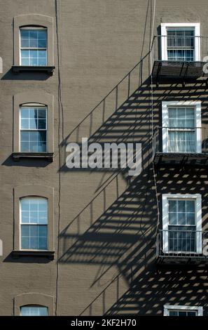 L'ombre du feu s'échappe sur le mur d'un petit immeuble d'appartements sur 10th Avenue et West 23rd Street dans le quartier Chelsea de New York. Banque D'Images