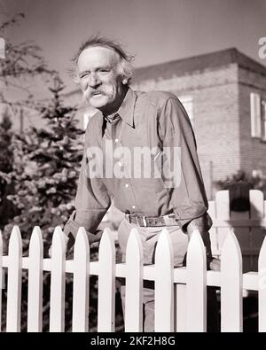 1940S HOMME ÂGÉ AVEC MOUSTACHE QUI S'EST APPUYÉ AU SOLEIL SUR UNE CLÔTURE BLANCHE AUTOUR DE SA PROPRIÉTÉ - S9716 HAR001 HARS SENIOR HOMME SENIOR ADULTE SENIOR B&W MOUSTACHE RETRAITÉ ANCIEN ÂGE OLDSTERS OLDSTER PROPRIÉTÉ MOUSTACHES EXTÉRIEUR FIERTÉ FACIALE MAISONS DE CHEVEUX ANCIENS IMMOBILIER STRUCTURES RÉSIDENCE HOMME ÂGÉ NOIR ET BLANC DÉCONTRACTÉ CAUCASIEN ORIGINE ETHNIQUE HAR001 À L'ANCIENNE Banque D'Images