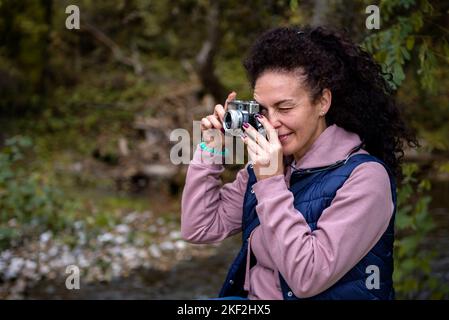 Femme photographe prenant des photos avec un appareil photo d'époque dans la forêt. Concept de voyage et de passe-temps. Banque D'Images