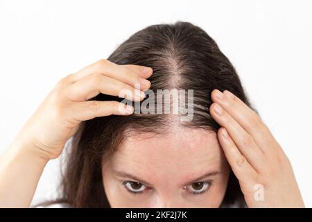 Gros plan de la femme contrôle la perte de cheveux et peu de volume avec les cheveux fins sur fond blanc Banque D'Images