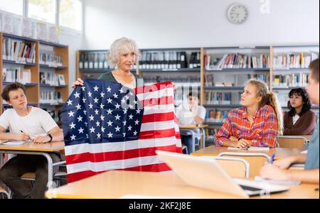 L'enseignante mature montre les jeunes enfants le drapeau national des États-Unis Banque D'Images