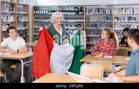 L'enseignante mature montre les jeunes enfants le drapeau national de l'Italie Banque D'Images