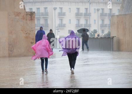 Valette, Malte - 12 novembre 2022: Personnes portant des ponchos de pluie et des parasols marchant un jour de pluie Banque D'Images