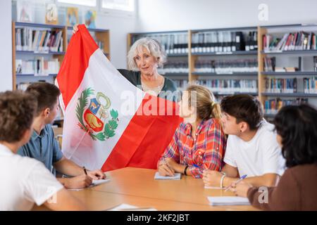 L'enseignante mature montre les jeunes enfants le drapeau national du Pérou Banque D'Images