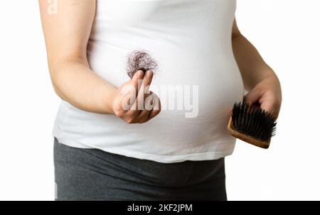 Femme enceinte montrant des cheveux tombés d'une main sur fond blanc Banque D'Images