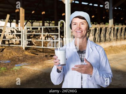 Certains hauts femme vétérinaire démontrant l'approuvant sur lait dairy farm Banque D'Images