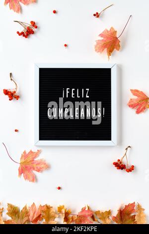 Feliz Cumpleanos texte signifie Joyeux anniversaire en langue espagnole. Feuilles d'automne, baies de rowan et accueil sur tableau de texte. Carte de vœux d'automne. Titre Banque D'Images