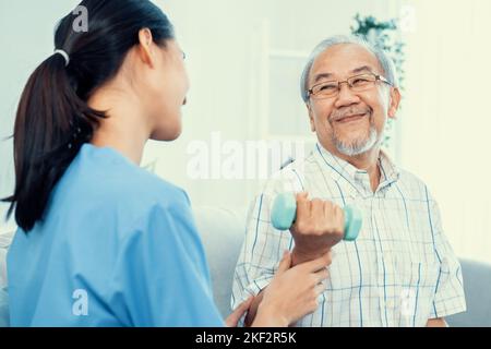 Un patient âgé ayant un niveau de satisfaction qui fait une thérapie physique avec l'aide de son soignant. Physiothérapie senior, traitement de physiothérapie, maison de soins pour le Banque D'Images