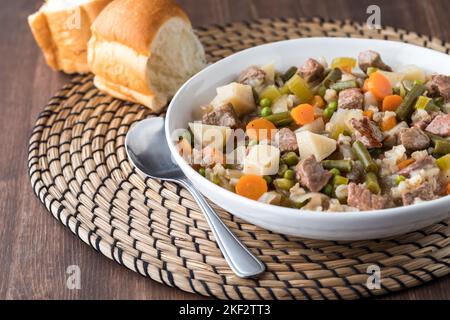 Un bol de ragoût de bœuf maison frais servi avec des petits pains. Banque D'Images