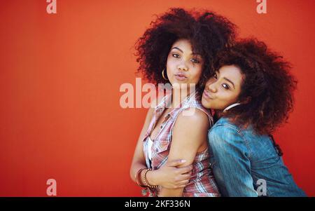 Rien n'est plus unique... avoir une bestie pour partager votre vie. Deux jeunes amis se posant sur un fond rouge. Banque D'Images