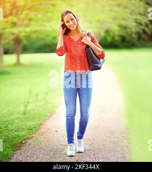 Être à l'extérieur met toujours un sourire sur mon visage. Une jeune femme sur une promenade dans le parc. Banque D'Images