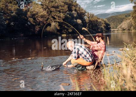 Pêcheurs hommes amis et truite trophée. Père et fils de pêche. Générations hommes pêche dans la rivière. Pêche à la truite. Banque D'Images