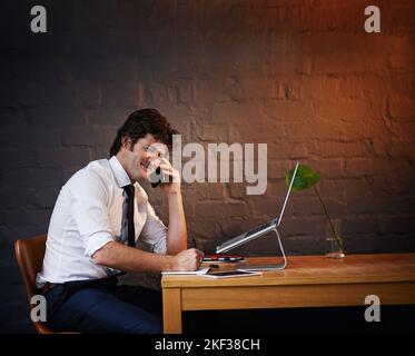 Bien sûr, nous pouvons le faire pour vous. Un homme d'affaires parlant au téléphone tout en travaillant tard au bureau. Banque D'Images