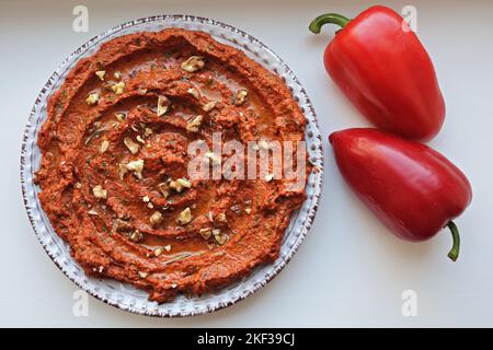 Muhammara, sauce de noix saines et poivrons rouges rôtis sur une assiette blanche en céramique. Copier l'espace Banque D'Images