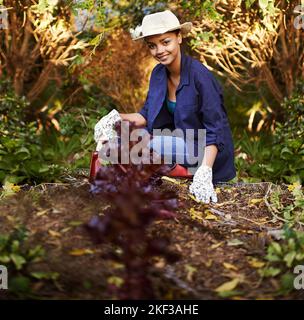 J'aime travailler la terre. Une jeune femme jardinant dans son arrière-cour. Banque D'Images