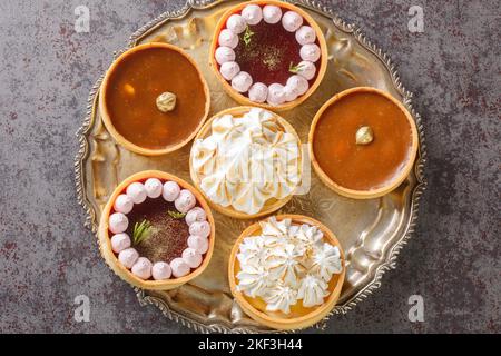 Ensemble de tartelettes de fête avec caillé de meringue et de citron, caillé de framboise, noix et chocolat sur une assiette sur la table. Haut horizontal vi Banque D'Images