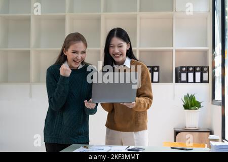 Une jeune équipe d'affaires asiatique célébrant un triomphe avec les armes. Banque D'Images