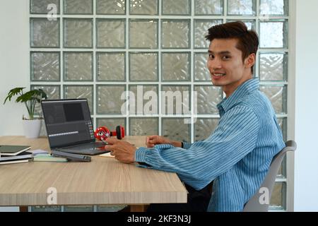 Un éditeur de vidéos asiatique travaillant avec des films et du son sur un ordinateur portable dans un bureau créatif moderne Banque D'Images