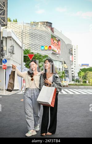 Portrait, deux jeunes femmes asiatiques surjoyeuses et heureuses avec leurs sacs d'achats, aimez marcher dans la rue commerçante ensemble. Banque D'Images