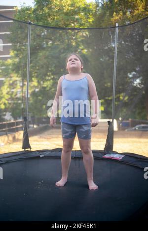 Elle sur son trampoline à l'extérieur de son pâté de maisons sur la route de Dacres. Banque D'Images