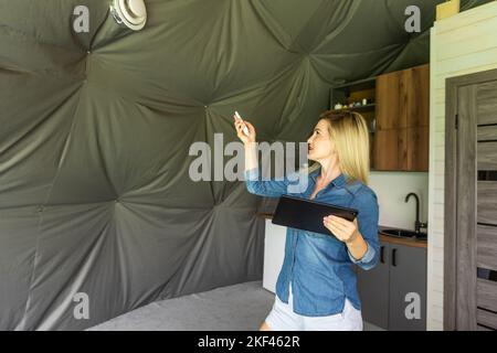 femme avec une tablette qui active le système de ventilation comme récupérateur pour la qualité de l'air frais à l'intérieur, maison intelligente Banque D'Images