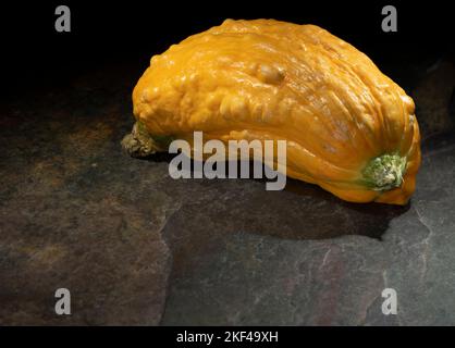 Courge jaune qui est petite sur une tuile beige, Banque D'Images