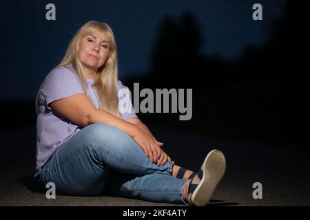 Femme d'âge moyen plexe posant dans des jeans dans la rue, poids excessif xxl. Une pleine fille aime la vie. Banque D'Images