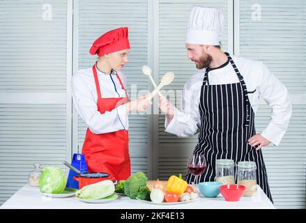 Femmes et hommes barbus lors de spectacles culinaires. Qui cuisinent mieux. Un défi de cuisine ultime. Bataille culinaire de deux chefs. Couple en compétition culinaire Banque D'Images