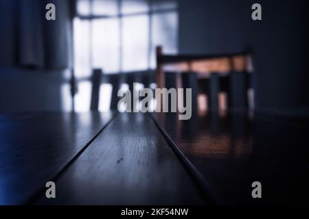 Lumière faible avec ombres projetées sur un mur avec table et chaise Banque D'Images