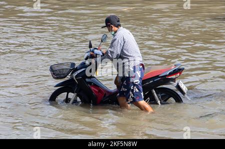 SAMUT PRAKAN, THAÏLANDE, OCT 29 2022, Un homme pousse une moto le long d'une rue inondée Banque D'Images