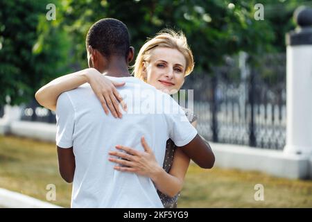 Portrait d'un jeune afro-américain debout avec le dos dehors et heureusement embrassant belle femme d'âge moyen. Affection, adieu Banque D'Images