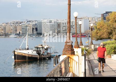 Sliema, Malte - 12 novembre 2022 : homme âgé marchant sur la promenade du front de mer tôt le matin Banque D'Images