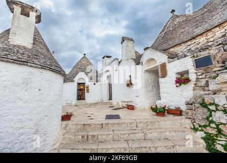 Belle ville d'Alberobello avec des maisons de Trulli parmi les plantes vertes et les fleurs, région d'Apulia, sud de l'Italie. Banque D'Images