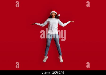 Magnifique modèle afro-américain féminin porter chapeau de père noël sauter vers le haut Banque D'Images