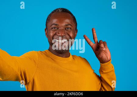 Homme mature afro-américain positif prenant le selfie et le gestuelle Banque D'Images