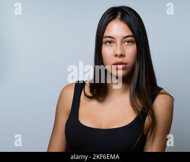 Gros plan de la femelle de Teen multiraciale assise avec les yeux intenses et les cheveux longs 90s vague Banque D'Images