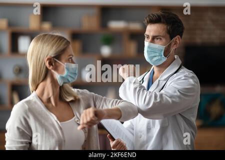 Un médecin portant un masque médical de protection se cognant les coudes avec une patiente Banque D'Images
