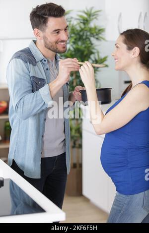 couple heureux cuisant ensemble dans la soupe de dégustation de femme de cuisine Banque D'Images