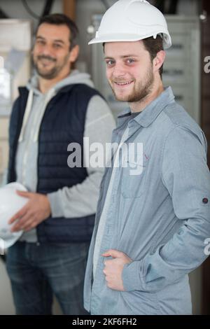 deux constructeurs de vêtements de travail souriant à la caméra Banque D'Images