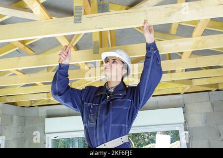 femme de construction utilisant un marteau pour travailler sur des poutres de toit Banque D'Images