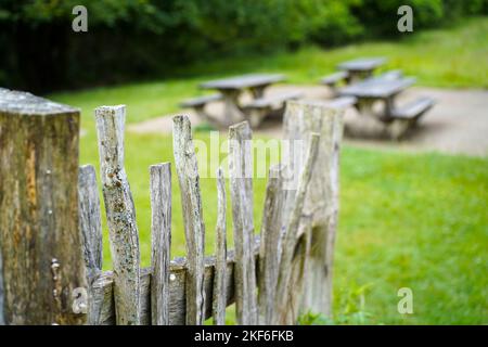 Gros plan sur une clôture rustique en bois de piquetage artisanale dans le parc national du Royaume-Uni menant à des bancs de pique-nique vides. Banque D'Images