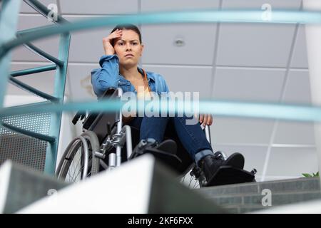 femme en fauteuil roulant bloquée par des escaliers Banque D'Images