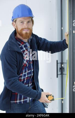 homme mesurant la porte dans la pièce outil de construction de fermeture Banque D'Images