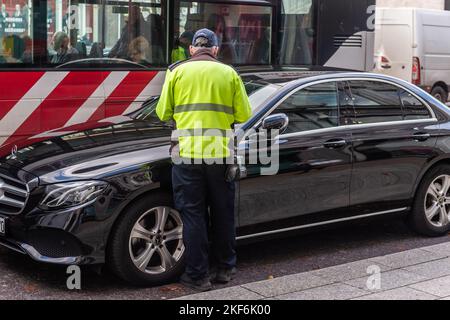 Garde-trafic émettant un billet de stationnement pour une voiture garée illégalement à Cork, en Irlande. Banque D'Images