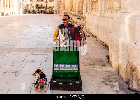 Un musicien de rue jouant avec son chien d'animal de compagnie, Ortigia, Syracuse (Syracuse), Sicile, Italie Banque D'Images