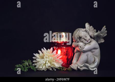 Bougie funéraire, figurine fleur et ange sur fond noir Banque D'Images