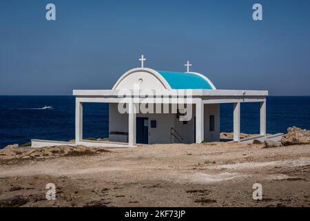 Ayia Napa, Chypre - 24 juin 2022: Agioi Anargiroi église blanche orthodoxe avec un toit bleu sur la côte du Cap Greco. Banque D'Images